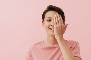 Asian brunette boy with dental brace smiling and covering his eye
