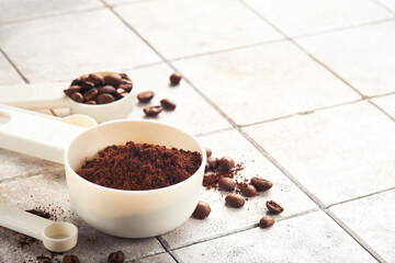 Coffee background. Measuring spoons with ground coffee and beans on old tile cracked table background. Ingredients for making coffee. Top view with space for your text
