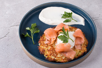 Fried draniki with red salted fish and poached egg. A dish decorated with herbs and sour cream