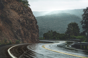 Scenic mountain winding road after rain. Green forest hills in the background covered by fog. Cape...