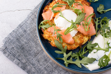 Fried draniki with red salted fish and poached egg. A dish decorated with herbs and sour cream
