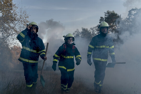 Firefighters Men At Action, Running Through Smoke With Shovels To Stop Fire In Forest.