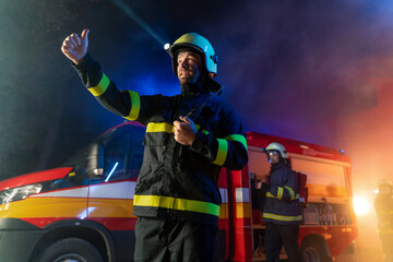 Low angle view of firefighter with fire truck in background at night.