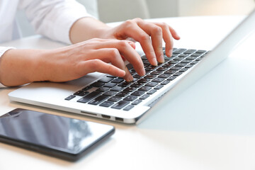 Fototapeta na wymiar Two hands typing on laptop at desk