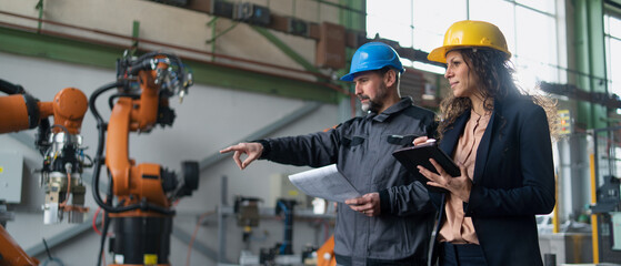 Female engineering manager and mechanic worker doing routine check up in industrial factory