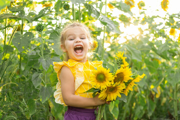 happy little kid girl playing in blooming sunflower field on sunny summer day