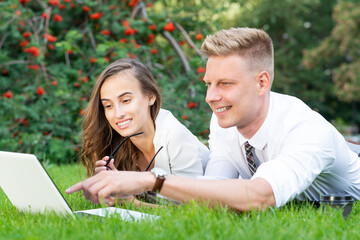 businessman and businesswoman with a laptop in a city park