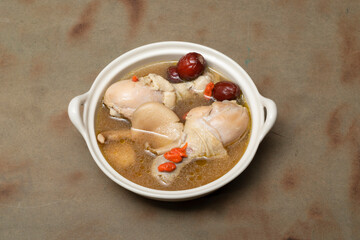 Chinese chicken soup has herb on wood table.