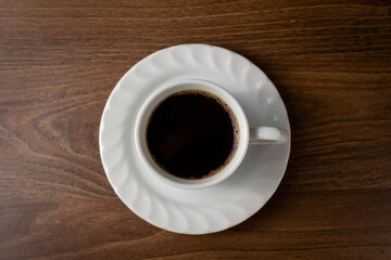 Dark coffee in white mug on wooden table..