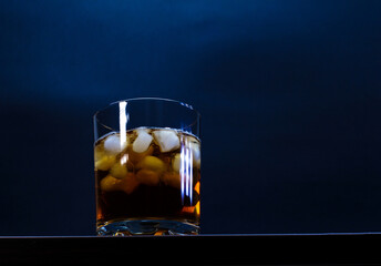 Whiskey glass with ice cubes on wooden table