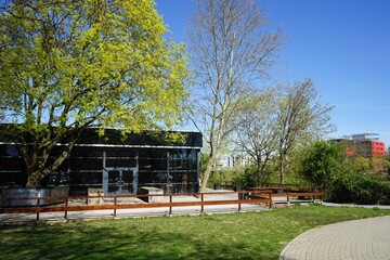 Moderne Architektur und grüne Parklandschaft im Frühling bei blauem Himmel und Sonnenschein am...