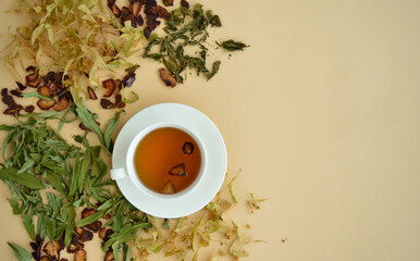 herbal tea in a white cup for beauty and health, dried herbs, linden flowers and strawberries lie around.