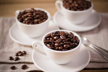 Three White Coffee Cups on White Saucers Filled with Coffee Beans