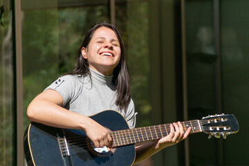 una mujer sonrriendo y tocando la guitarra en un dia soleado
