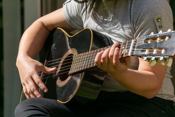 Fototapeta na wymiar manos tocando una guitarra antigua en un dia soleado
