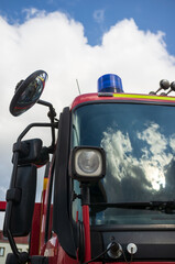 Fototapeta premium Fire engine with reflective sky and clouds on the windshield. Rescue and safety concept. Close-up.