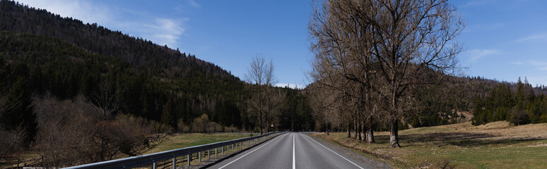 Fototapeta premium Empty road, mountains and trees with sky at background, banner.