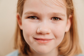 Naklejka premium portrait of a cheerful little girl with blonde hair in a blue T-shirt. happy childhood. Emotions.