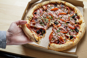 The hand takes a piece of pizza. Pizza party. Hot italian pizza, top view