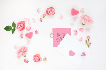 Layout made of flowers, letter with a valentine, engagement ring on white background. Top view. Love confession. 