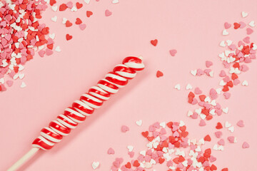 Background of brightly colored candy hearts and candy lollipop for Valentine's Day. Candies hearts of pastel colors on pink paper. Top view. Love hearts background Valentine's Day background. 