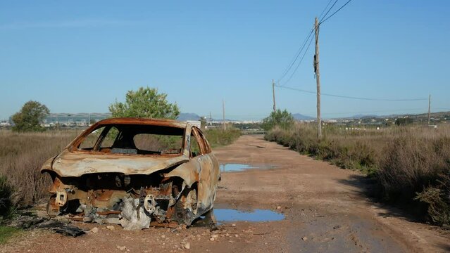An old abandoned and rusty car on a dirt road outside the city and away from the highway
