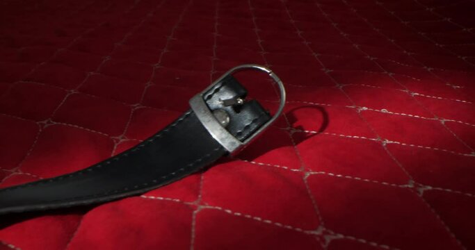 detailed, extreme close-up round gag on leather straps on a red blanket