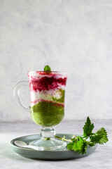 Delicious dessert with a layer of yogurt, nettle smoothie and honeysuckle jam. Dessert is served in a glass with a spoon. Copy space