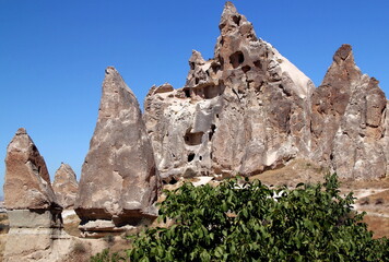 Mushroom-shaped rocks (also called the Fairy Chimneys) with caves inside in the Rose Valley between the towns of Goreme and Cavusin in Cappadocia, Turkey