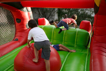 Boys playing in inflatable game. Childrens climbing on inflatable castle. Children's birthday. Fun...