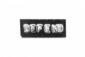 Black color banner that have embossed letter with word defend on white paper background