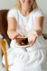 Third anniversary mini chocolate cake. Mother holding a cake in her hands