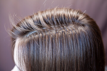 Bundles of hair extensions on a woman's head. Hair extensions to thicken your own. Individual strands of hair close-up