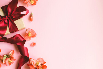 Obraz premium Happy Mothers day. Stylish gift box with red flowers on pink background border. Greeting card template with space for text. Festive craft gift with ribbon and flowers. Women's day