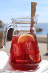 Glass pitcher of sangria on ocean front table