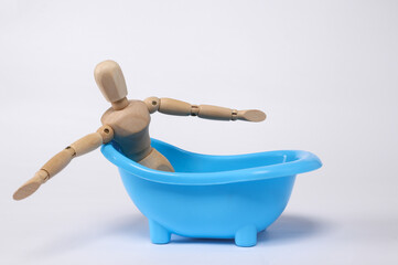 Wooden puppet relaxing in bathtub isolated on white background