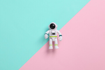 Astronaut toy model on pink blue background. Space mission