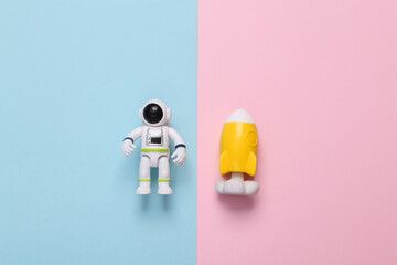 Astronaut toy model with space shuttle on pink blue background. Space mission