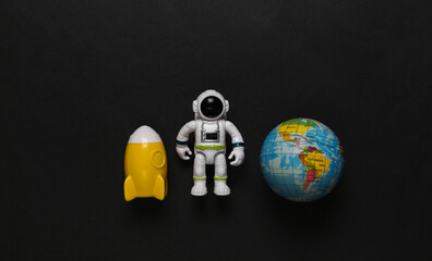 Astronaut toy model with space shuttle and globe on black background. Space mission. Flat lay