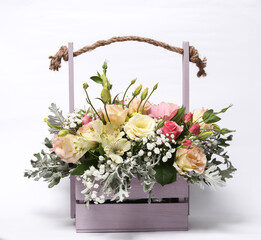 Beautiful bouquet of different flowers in a wooden basket isolated on a white background.