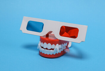 Halloween, entertainment concept. Vampire clockwork jaw with 3d glasses on a blue background