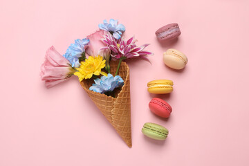 Romantic flat lay. Waffle cone with different flowers and macaroons on pink pastel background. Creative layout. Flat lay. Top view