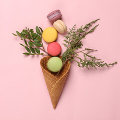 Romantic, food flat lay. Waffle cone with green twigs  and macaroons on pink pastel background. Creative layout. Flat lay. Top view