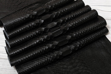 black dyed genuine natural python leather on the wooden table	
