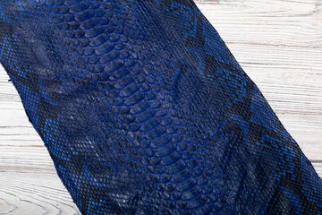 dark blue dyed genuine natural python leather on the wooden table	