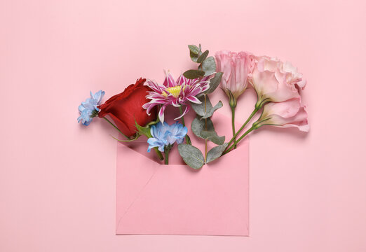 Beauty, love, romantic concept. Envelope with flowers on pink background. Top view. Flat lay