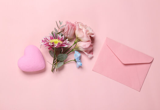 Beauty, love, romantic concept. Envelope with flowers and heart on pink background. Top view. Flat lay