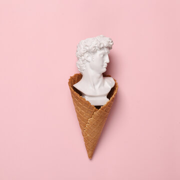 Creative minimal layout. Waffle cone with David bust on a pink background. Flat lay