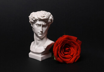 Romantic, valentine's day concept. David bust with red rose isolated on black background