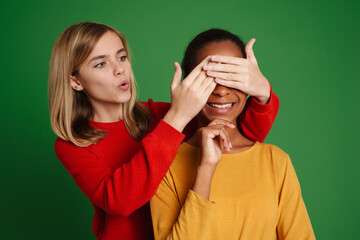 White girl expressing surprise while covering her friend's eyes